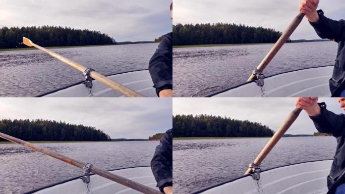 一个年轻人漂浮在湖上的船上。排桨。
