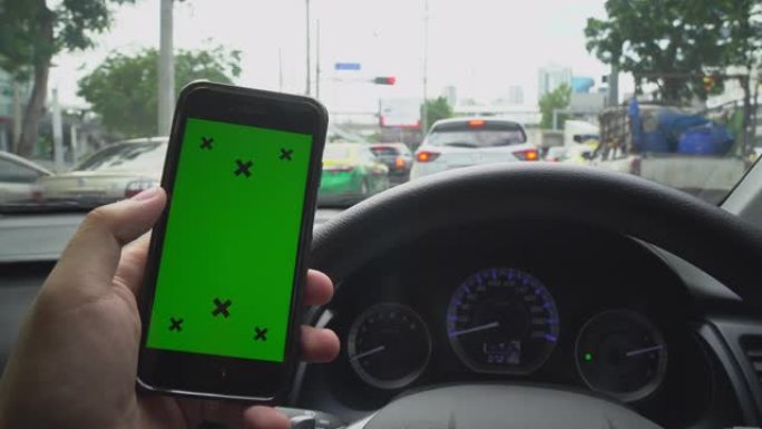 手持智能手机的特写镜头，看着汽车上的绿屏色度键显示。使用手机通过滚动、滑动、手指触屏。
