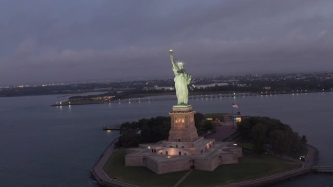空中: 盘旋的自由女神像在清晨的灯光下美丽地照亮了4k纽约市
