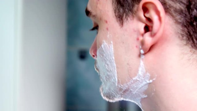 男人的脸上满是泡沫，他开始刮胡子