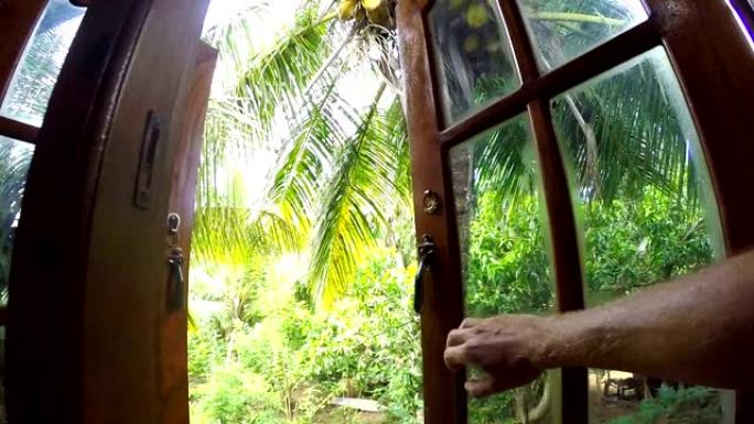 相机朝男性手打开的棕榈树花园窗户移动。生活在异国自然概念视点视频。