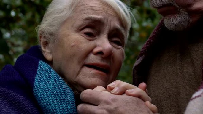 老妇哭着牵着配偶的手，退休人员的社会不安全感