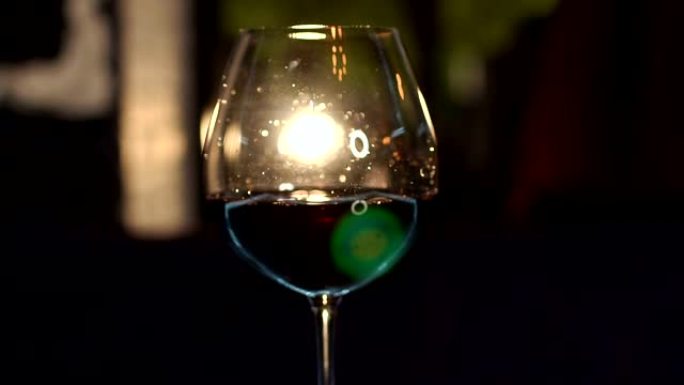 一杯红酒在模糊的黑暗背景上的特写镜头。慢动作。