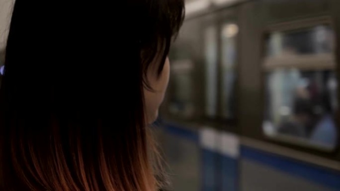 女人站在火车驶来的背景下的地铁站