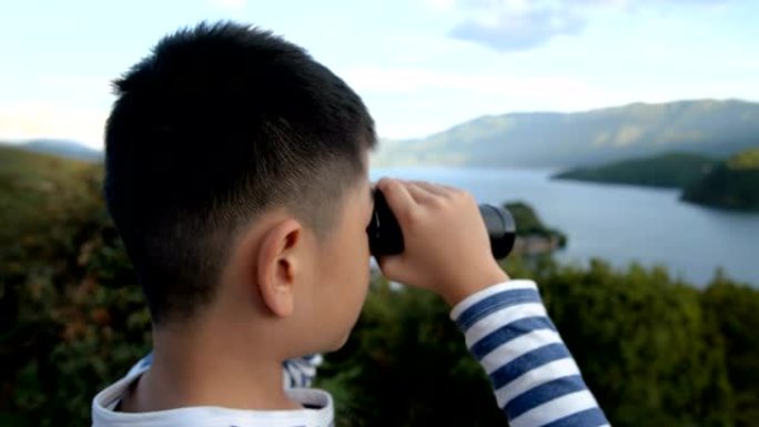 亚洲男孩用双筒望远镜看泸沽湖