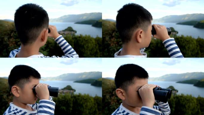 亚洲男孩用双筒望远镜看泸沽湖