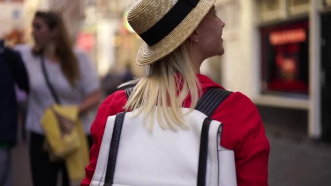 戴着帽子的快乐印象深刻的时髦女孩旅行者在城市漫步，享受当地的氛围