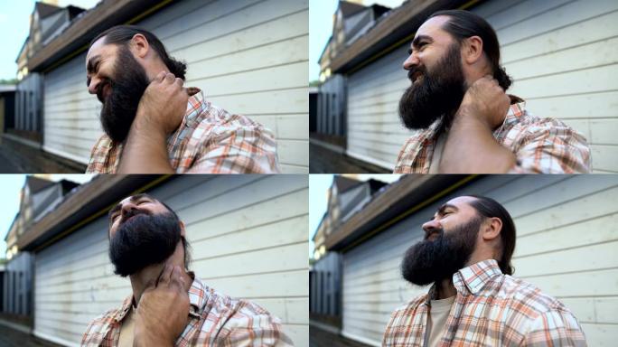 大胡子男性按摩颈部以缓解疼痛，肌肉痉挛，骨软骨病