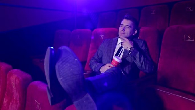 成功的商人坐在空荡荡的剧院里独自看电影。