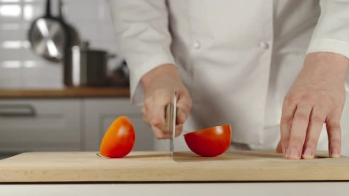 慢动作: 厨师在烹饪时在木板上切碎整个红番茄