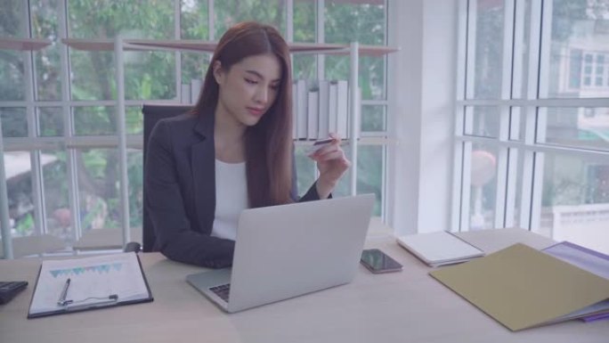 肖像亚洲美丽的女孩或女人用电脑在工作场所做生意。网上购物，转账，网上银行，幸福意味着一切作为灵感概念