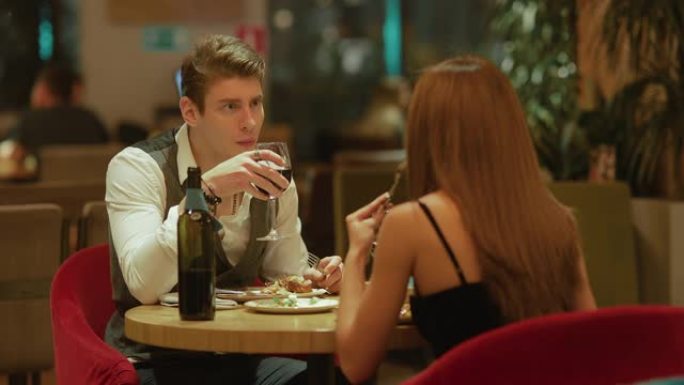 年轻英俊的男人和一个漂亮的女人在餐馆吃饭，喝葡萄酒。已婚夫妇正在吃饭和聊天。