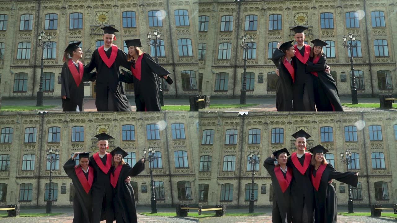 三个穿着黑色和红色衣着的快乐学生在大学大楼前庆祝毕业。