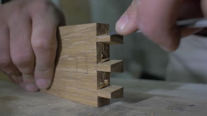 特写镜头，木匠在工作台上用凿子在木制零件上做燕尾榫。木工加工橡木细节。4k. 4k视频。慢动作。24