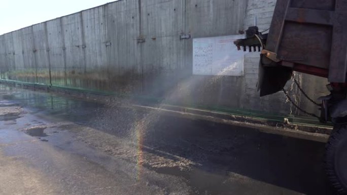 特写。汽车在纳霍德卡 (Nakhodka) 的煤炭贸易港口倒入干净的煤尘中弄脏的沥青。湿洗。
