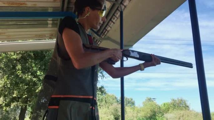 在射击场双向飞碟射击练习中，中年妇女重新装填猎枪