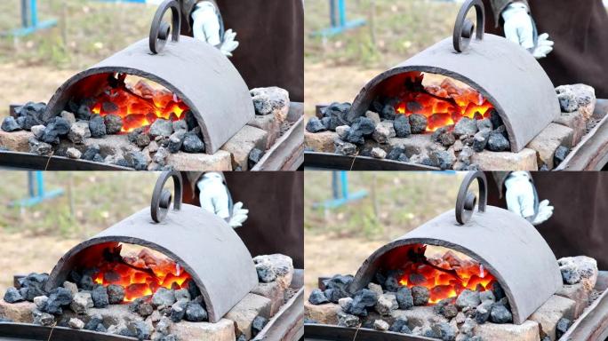 铁匠在热煤中加热钢坯，并准备锻造钢花