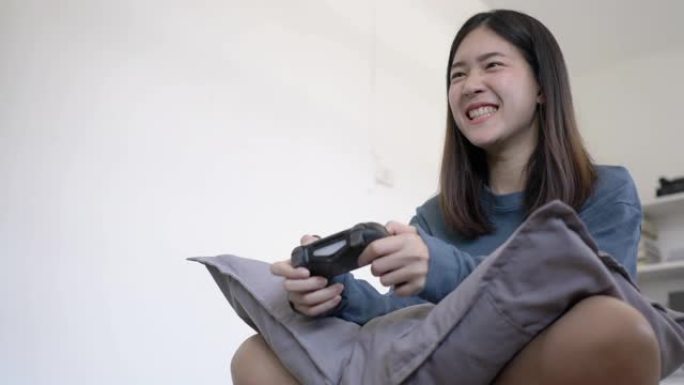 亚洲少女在家里的卧室里玩电子游戏快乐和激动人心的情感。使用操纵杆控制游戏。教育、科技、娱乐和放松的概