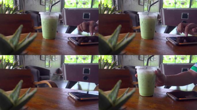 男人用智能手机喝绿茶