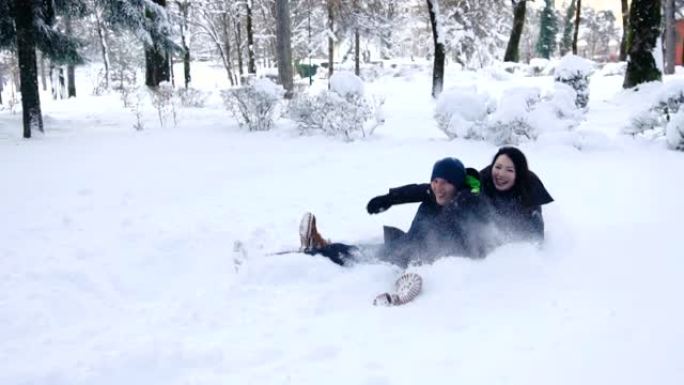 快乐的夫妇在冬季森林里打雪仗和在雪地里玩得开心