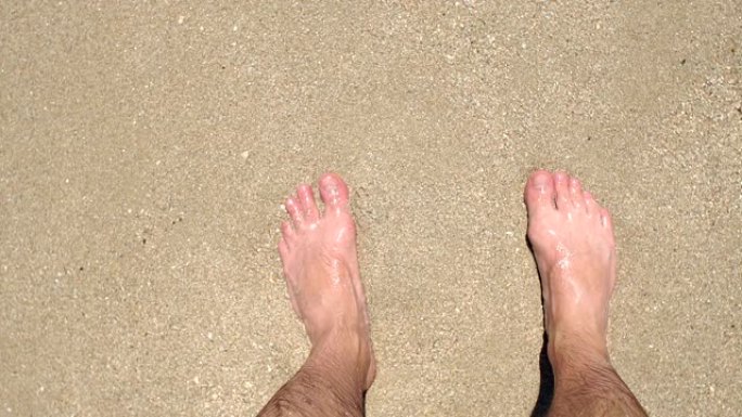 男人的脚在海上的沙子上的特写。从上往下看。