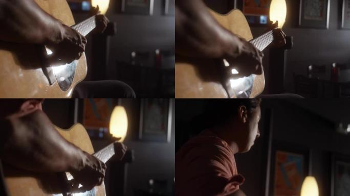在昏暗的咖啡店里，一位拉丁裔男性音乐家从背后演奏原声吉他的特写镜头