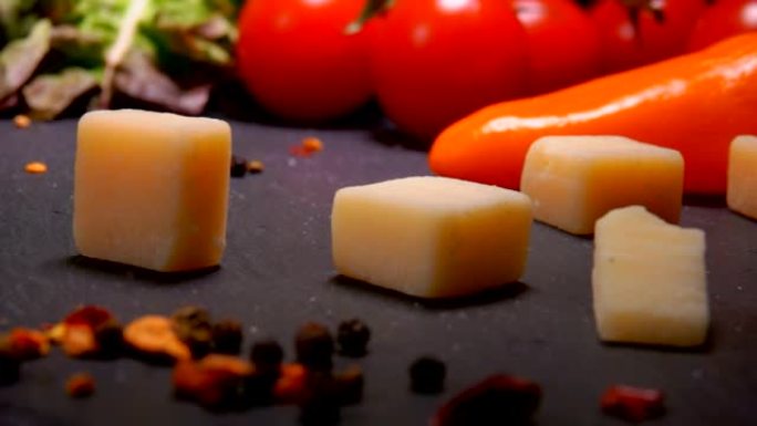 硬奶酪块掉落在带有胡椒粉的黑色表面上