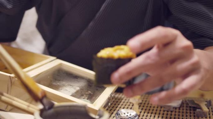 一名厨师用筷子烹饪，并在日本omagase餐厅放入shoyu酱海胆日本料理。