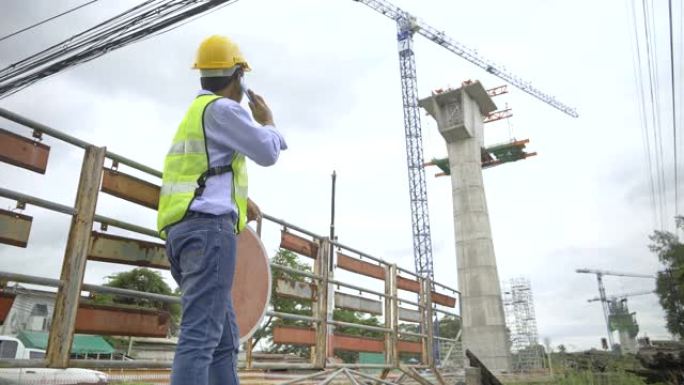 4k镜头，亚洲土木工程师和欧洲土木工程师专家讨论和讨论手持剪贴板、平板电脑、对讲机和戴安全帽的铁路建