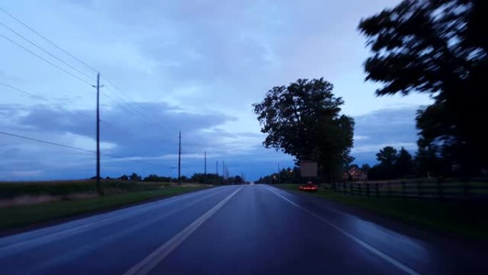 开车穿过乡村，接近地平线上的城市灯光。驾驶视点POV在白天驶向城市极限。
