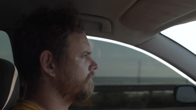 留着胡子的男人开着一辆表情殷勤的汽车。那家伙在大海的背景下开车。4k. 4k视频。慢动作。23.98