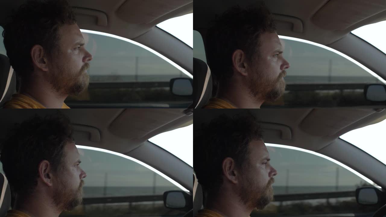 留着胡子的男人开着一辆表情殷勤的汽车。那家伙在大海的背景下开车。4k. 4k视频。慢动作。23.98