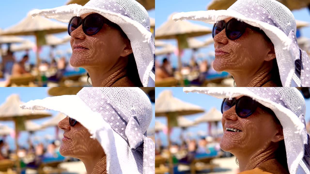 海滩美女戴草帽眼镜保护，看距离微笑背景模糊伞，真实镜头