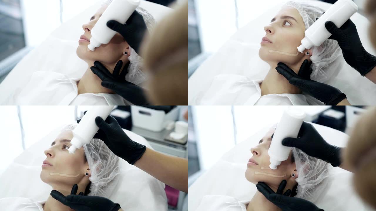 美容师戴手套的慢动作特写手在治疗前将特殊凝胶涂在患者脸上