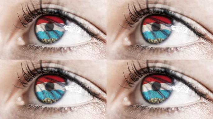 女人绿色的眼睛在近距离与卢森堡旗在虹膜与风的运动。视频的概念