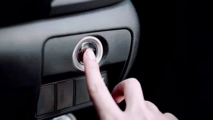 启动汽车发动机，手指按下按钮启动汽车发动机。