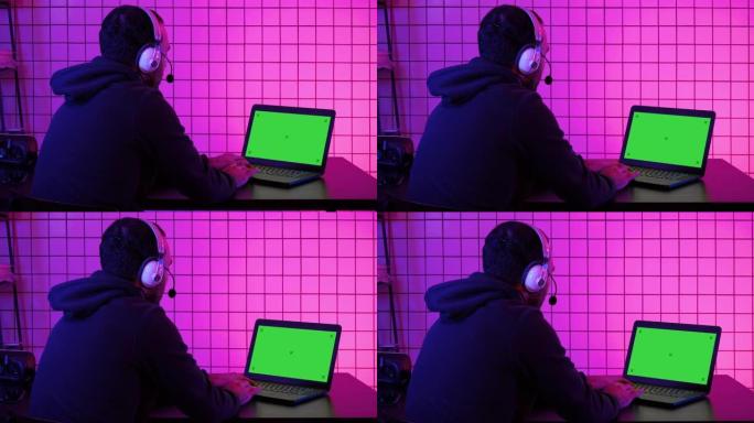 职业玩家在笔记本电脑上玩电子游戏。绿屏模拟显示