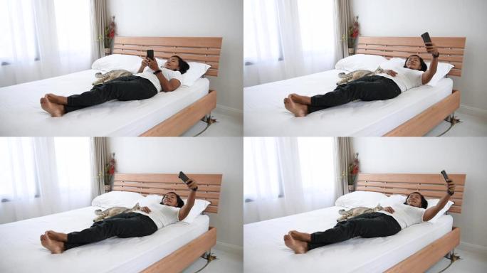 亚洲女性使用智能手机自拍，在现代卧室玩虎斑猫。