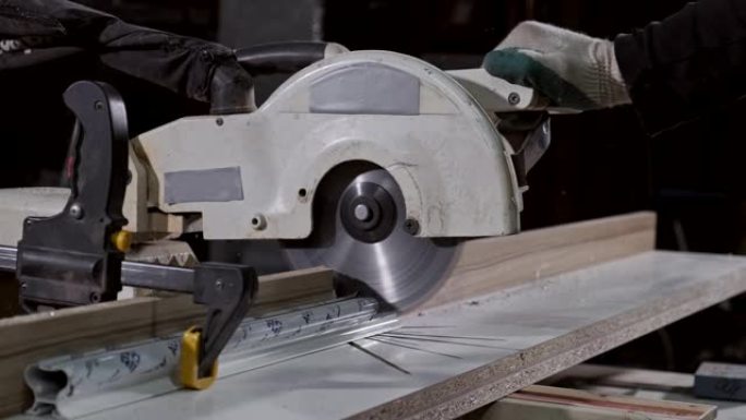 木匠用圆锯切割金属棒。带桌子圆锯的人