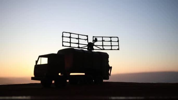 创意艺术品装饰。日落时带雷达天线的移动式防空卡车的轮廓。卫星天线或无线电天线对着夜空。选择性聚焦
