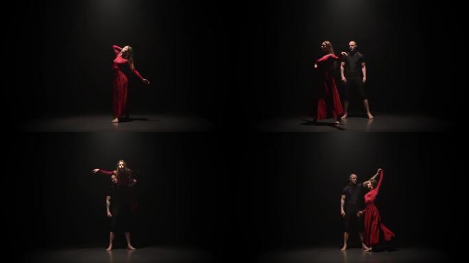 在黑暗的工作室里，女人和男人在聚光灯下的黑色背景上跳舞。慢动作