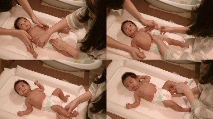 亚洲父母在洗澡后，在家，孩子cre更换婴儿尿布