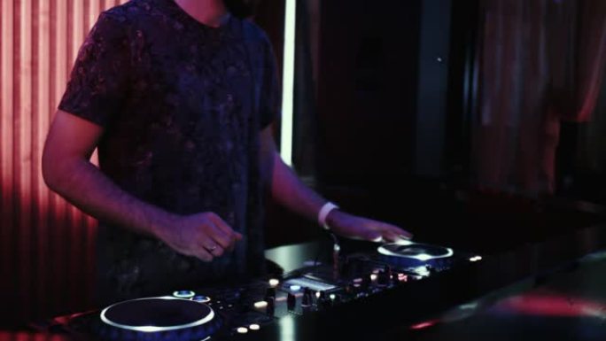 控制台上的DJ在夜舞俱乐部中混合音乐
