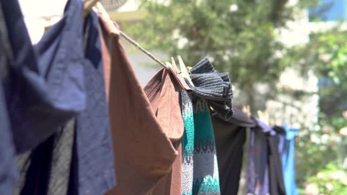干净的洗过的衣服挂在电线上，带有衣夹和模糊的春季自然背景。
