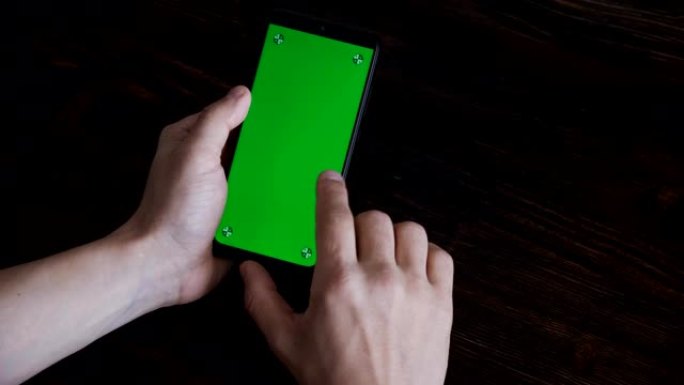 绿屏手机的特写镜头。智能手机屏幕上的色度键。一个人在手机屏幕上滚动信息。点击并滑动。准备绿屏插入信息