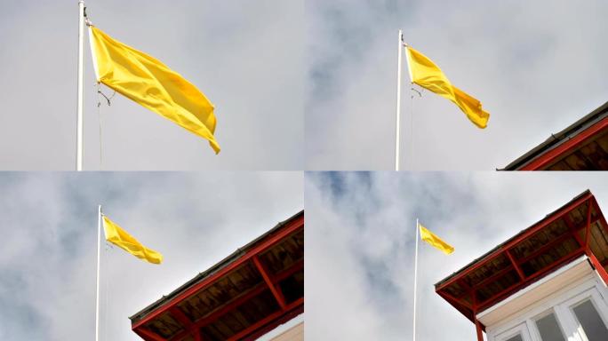 海滩边的长杆上挂着一面黄色的旗子