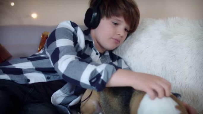 4k儿童戴着耳机和爱抚狗听音乐