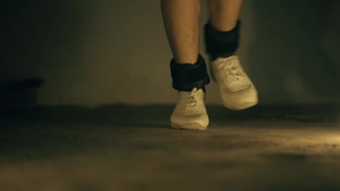 腿部穿着白色运动鞋和黑色脚踝重量，并进行拳击手跳跃运动。