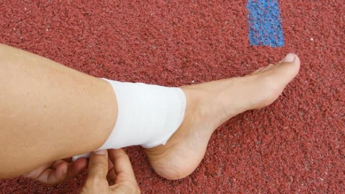 女孩用绷带包扎她的脚踝