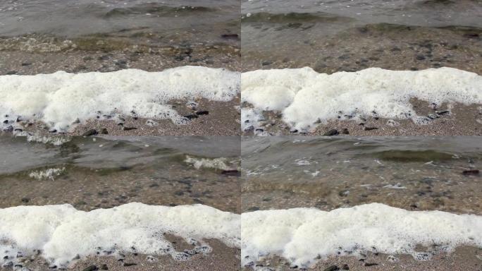 波浪在河岸上滚动，用泡沫敲打石头